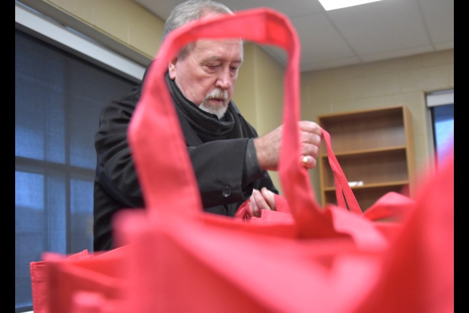 Community volunteer Ken Clarke grabs some of the Winter Warmup campaign bags before distributing them to local seniors Jan. 10.