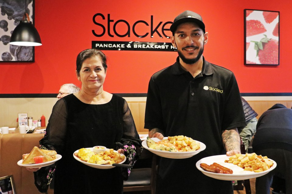 From left: Owner Seema Hashmi and son Shakaib Hashmi bring out plates stacked with breakfast foods for customers during the grand opening of Stacked Pancake and Breakfast House in Unit 5 at 494 Holland St. W. in Bradford on Dec. 4.