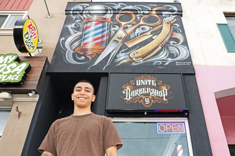 Owner, Yonatan Ben Lulu (YB) stands in front of Unite Barbershop at 18 Holland St. W. in Bradford on June 7, which was transformed with a new mural two days earlier, featuring hand painted images of a barber pole, scissors and a razor.