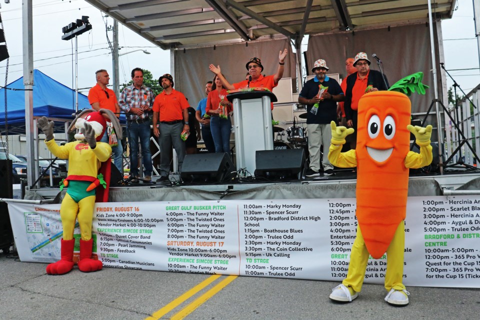 Mascots Captain Carrot and Gwilly stand in front of the stage as Mayor James Leduc, members of council, and federal and provincial politicians announce the official opening of Carrot Fest 2024 in downtown Bradford on Friday.