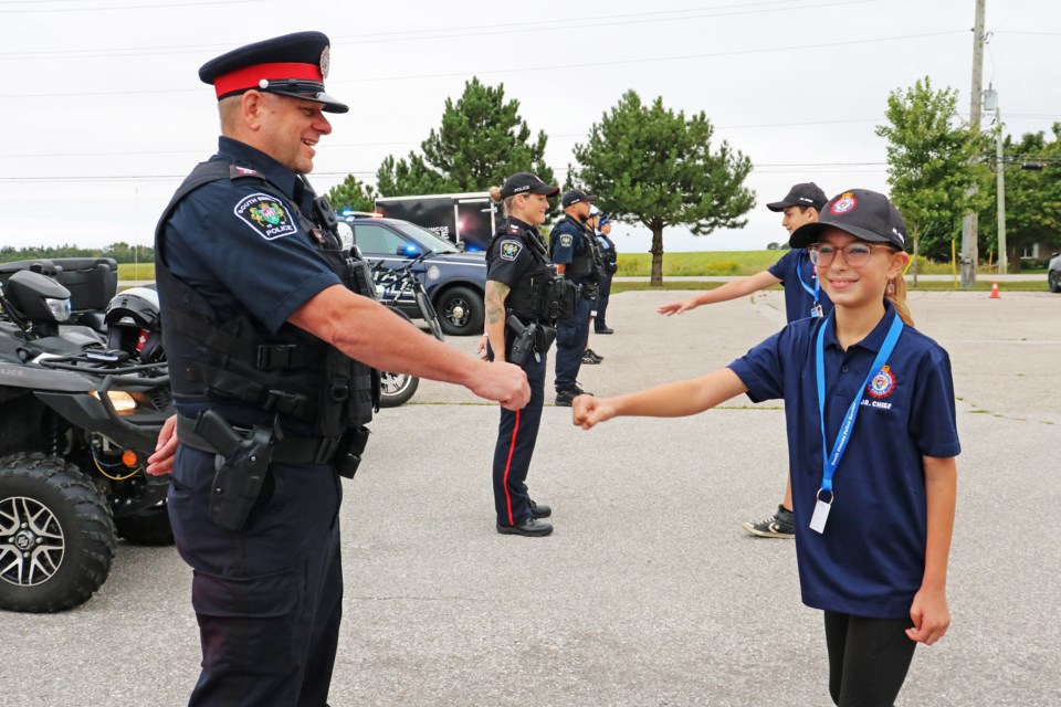 Noelle Peirce fist bumps an officer during an inspection by her and Daniel Barkan, who were sworn in as the junior chiefs for the day at the South Simcoe Police Service’s North Division building in Innisfil on Aug. 28.