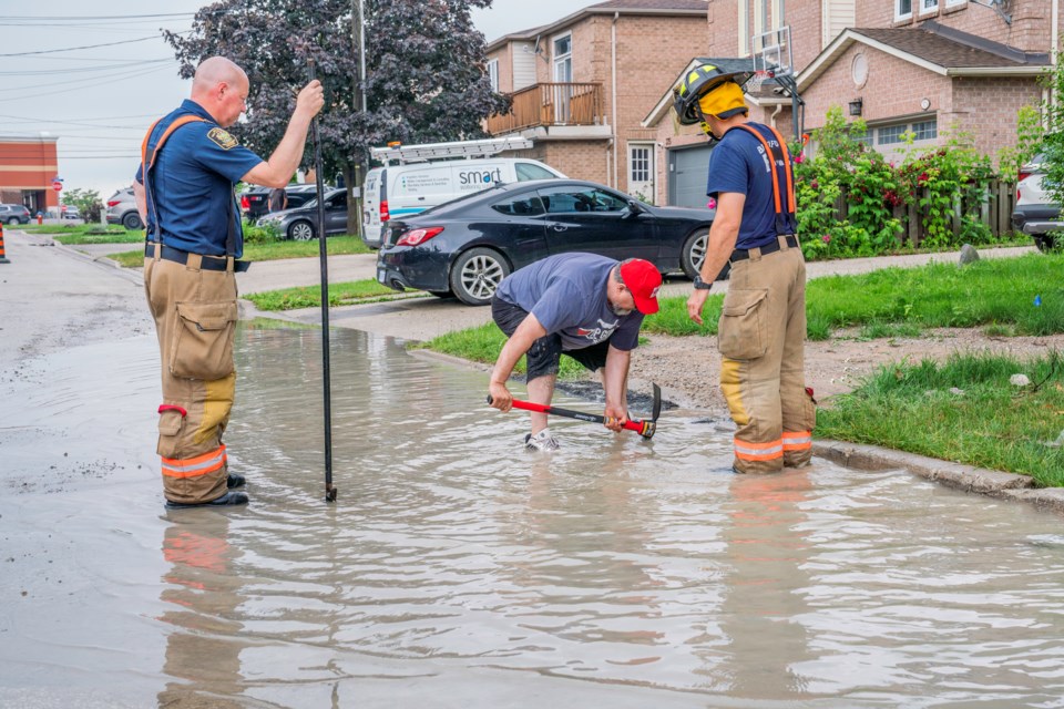 Bradford Fire and Emergency Services crews worked with residents to relieve flooding issues on Agar Avenue Saturday afternoon. Here, a storm sewer is about to be opened to help drain the water. 