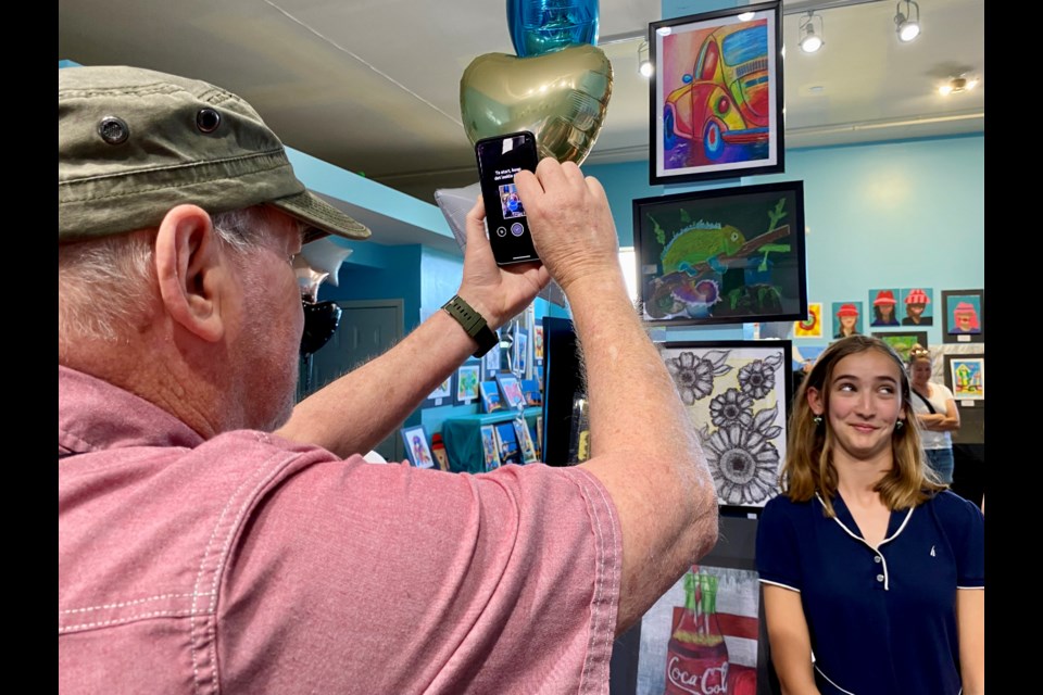 Brooke Belknap poses next to some of her art as her opa photographs the moment.