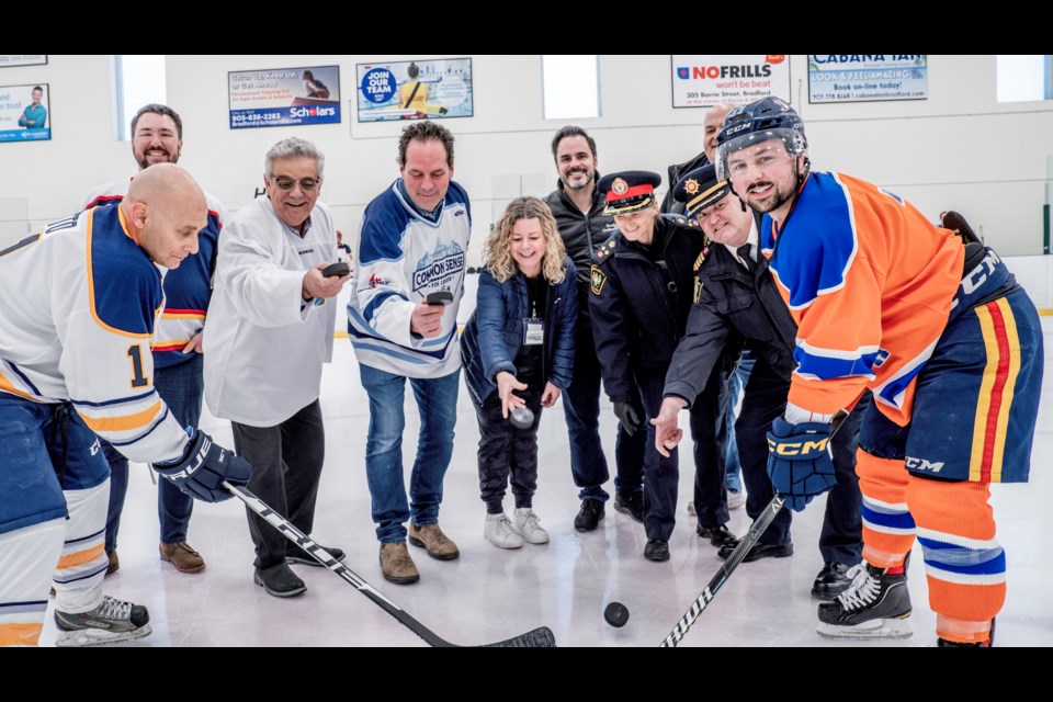 Dropping the puck are Bradford Mayor James Leduc, MP York-Simcoe Scot Davidson, Helping Hand Food Bank's Carolyn Khan, South Simcoe Police Service Deputy Chief Sheryl Sutton and Bradford Fire and Emergency Services Deputy Chief Steve Hall. 