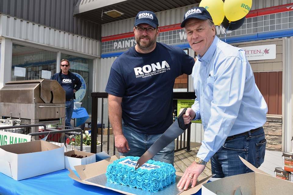 Dennis Doidge, right, and Brad Bartlett cut the cake, at the 100-year celebration at RONA in Bradford. Miriam King/Bradford Today