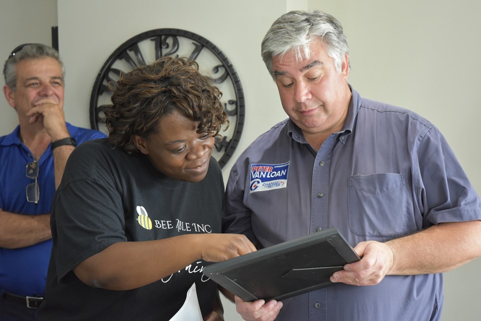 Claudett Bailey views a certificate presented by York-Simcoe MP Peter Van Loan at the opening of Bee Able Inc. Miriam King/Bradford Today