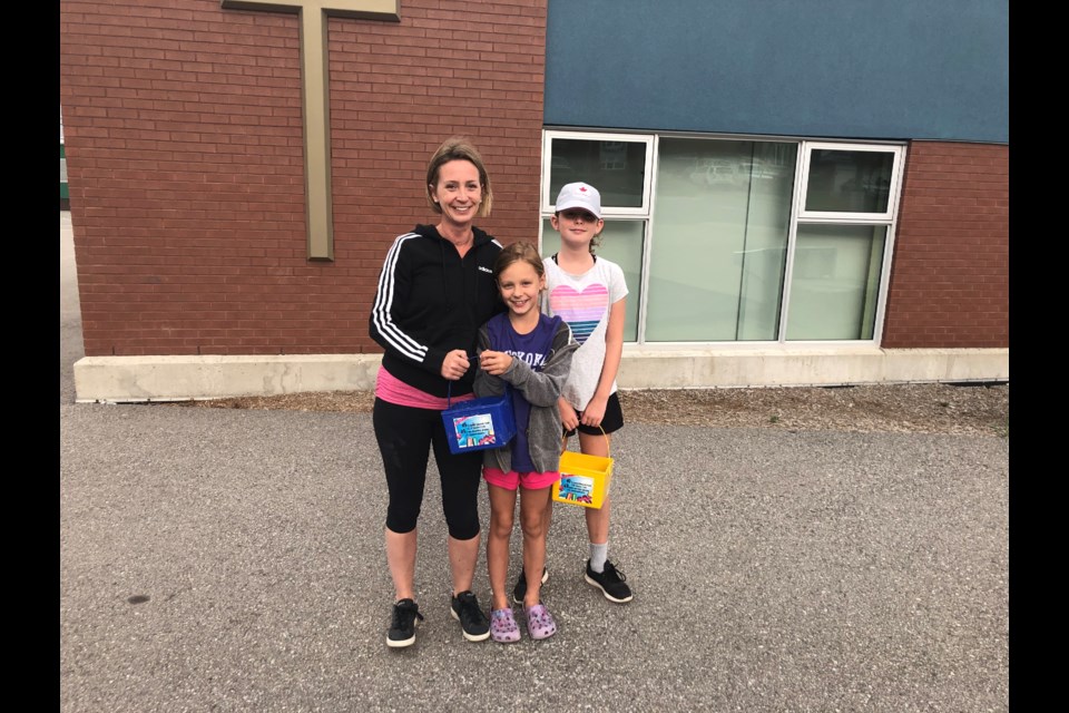 Diane Osborne and her two daughters, Reese, 8, and Rylie, 10, write inspiring messages with chalk before the first day of school. Natasha Philpott/BradfordToday