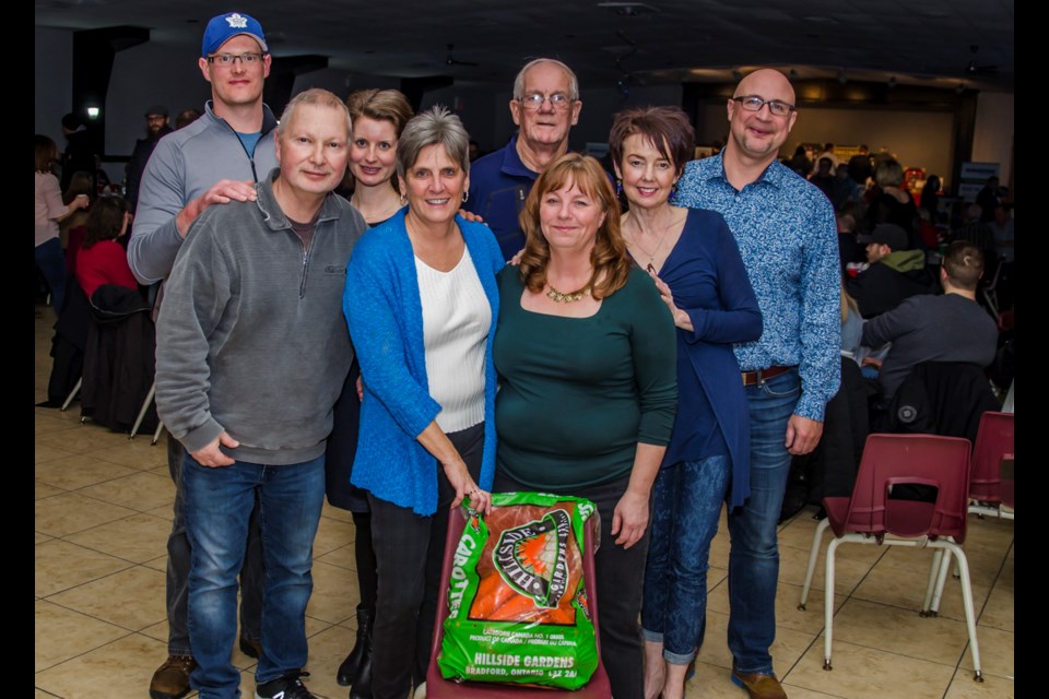 The Bradford Curling Club fundraising committee poses for a moment of recognition during An Evening of Comedy fund raisier. (from left to right) Nick Miedema, Glenn Goshulak, Theresa Miedema, Cathie Heppell, Wally Kemp, Kim Moyles, Carmel Kryskow, and Brian Febel. The carots were generously donated by Hillside Gardens. Dave Kramer for BradfordToday.