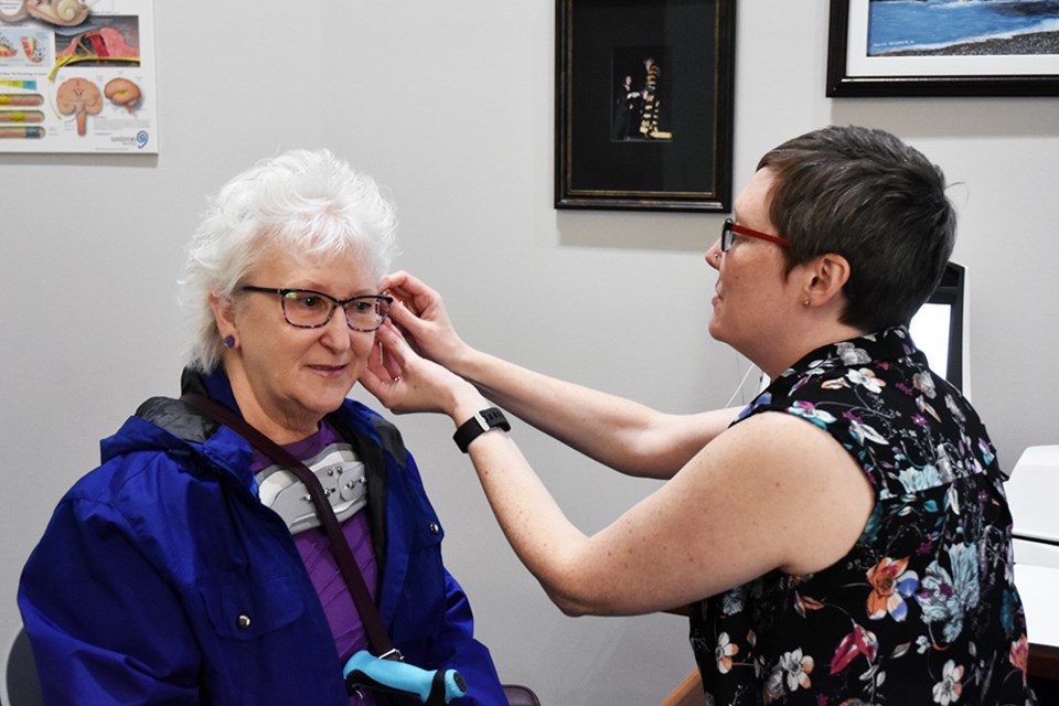 Audiologist Terra Fehrman, right, adjusts a hearing aid for Theresa Warner, at HearingLife. Miriam King/Bradford Today