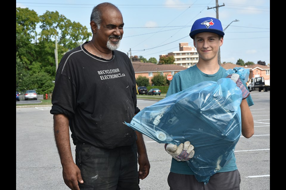 Ram Faerber, left, encourages young volunteer to unload electronics dropped off by a resident. Miriam King/BradfordToday