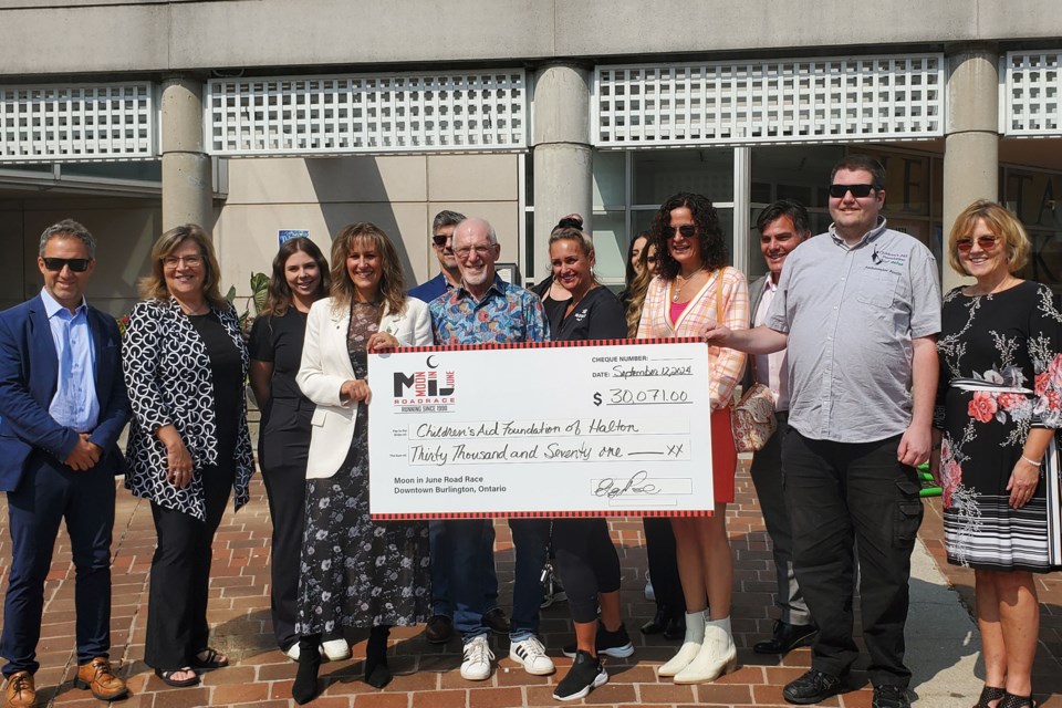 Local politicians, Moon in June organizers, race sponsors and representatives from the Children's Aid Foundation of Halton hold up the cheque.