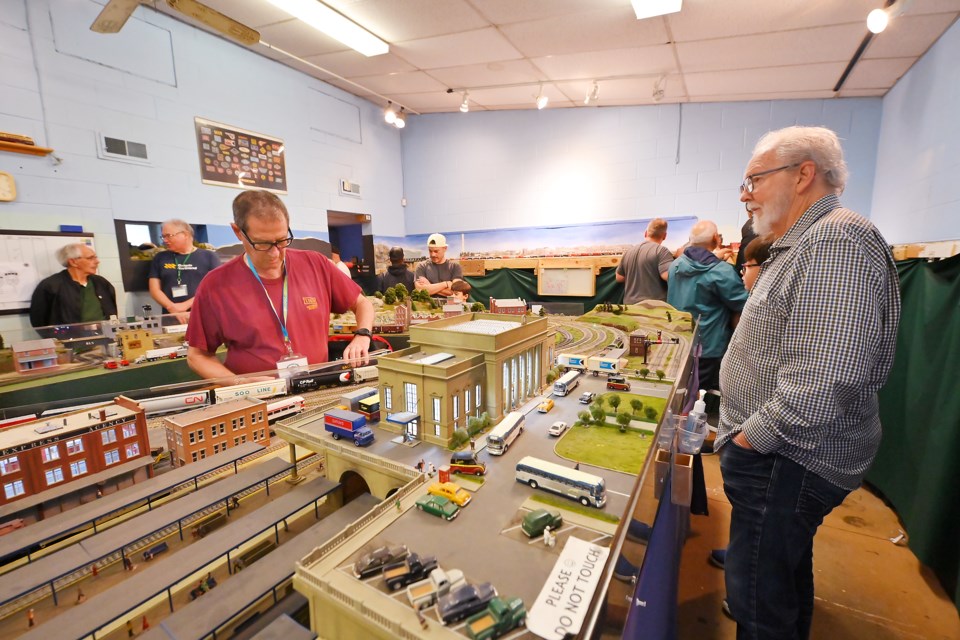 Barry Upiter works on train cars while being observed by Dennis Bolken during the open house at the Burlington Model Railway Club's facility on Hidden Valley Road Saturday.