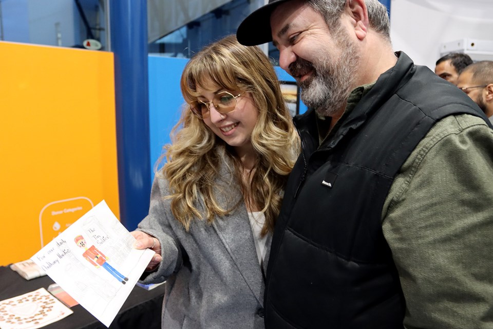 Krystal Hardie shows her dad, Tony, a Valentine's card she made for him when she was four years old that was placed in the time capsule inside the giant tin soldier. Tony Hardie was a welder on the project to build the tin soldier. MARIO BARTEL/NEW WEST RECORD