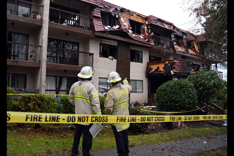 Burnaby fire chiefs survey the damage to an apartment building that went up in flames on Jersey Avenue Tuesday morning. 