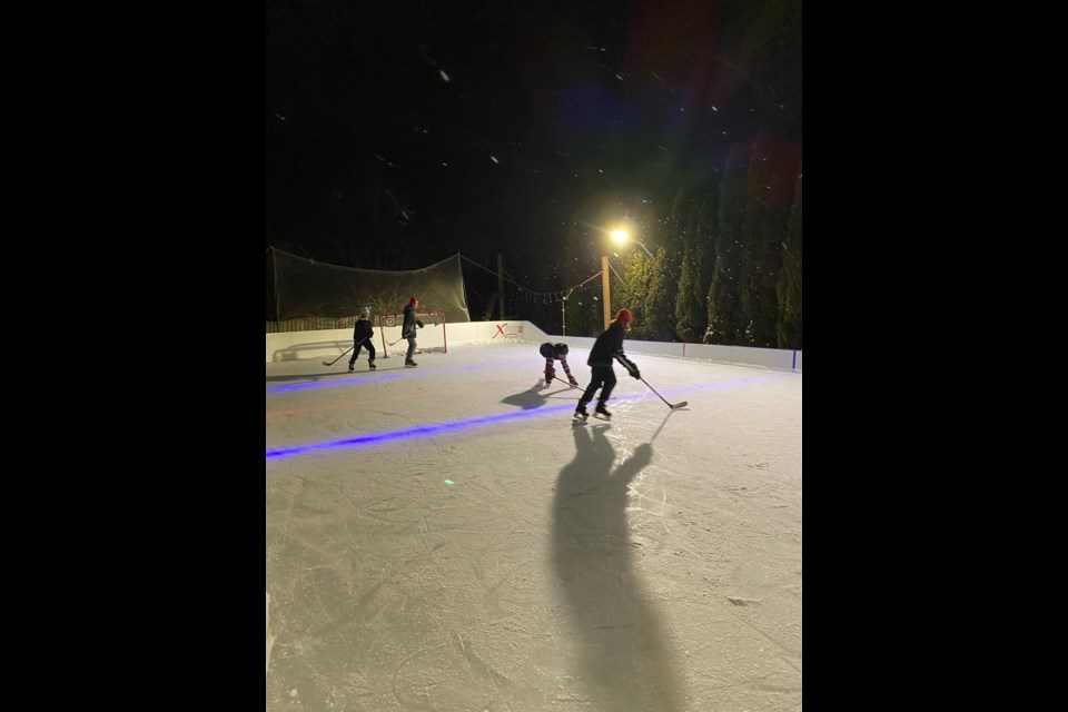 The Zilinski Family in Cambridge  playing hockey on their backyard ice rink. 