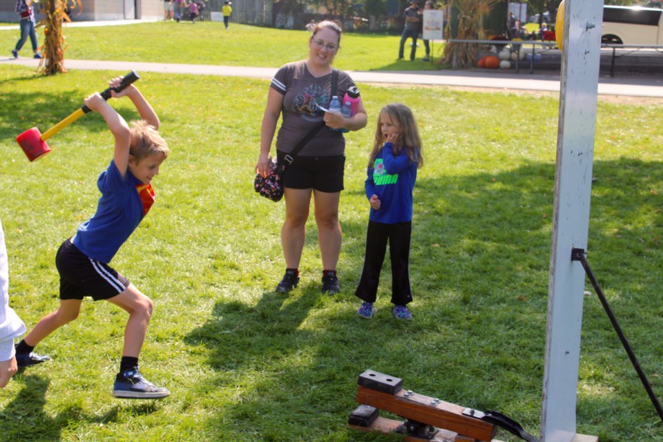 A young person tests his strength at the Harvest Festival in Forbes Park Saturday.