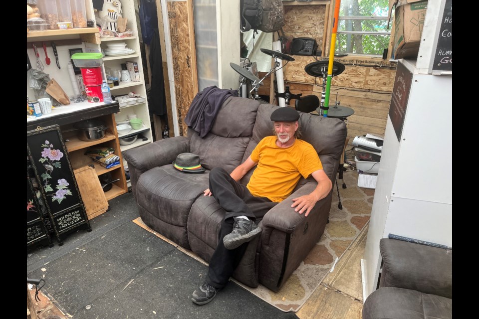 Brian Kitchen sits in the living room of his self-made shelter on Samuelson Street. It's his solution to surviving without a home.