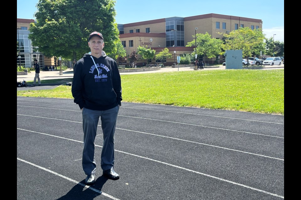 Laurel Creek Track and Field coach James Porto stands on the track at St. Benedict Catholic Secondary School. Also a math teacher at the school, Porto is pushing for more investments in local facilities.