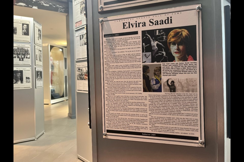 Elvira Saadi's plaque will remain on display in the Cambridge Sports Hall of Fame despite being given a lifetime ban from coaching athletes by Gymnastics Canada for "maltreatment and abuse."