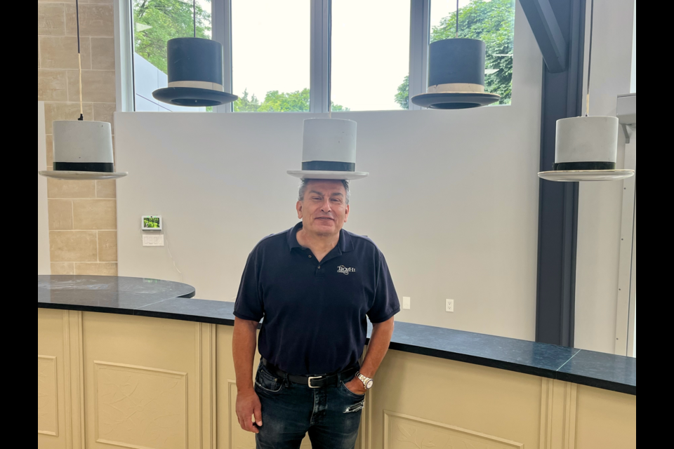 Jack Hougasian, owner of TechHi Consultants, stands under the famous top hats inside the old Knotty Pine restaurant. The hats are staying as his company is taking over the space.