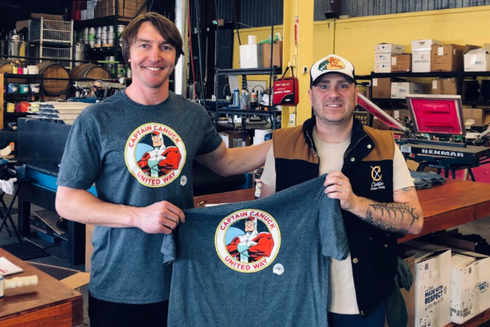 Scott Hamilton (left) of the United Way Waterloo Region Communities shows off a Captain Canuck shirt alongside Joe Zimmer, the operations manager at Civilian Screen Printing in Kitchener.