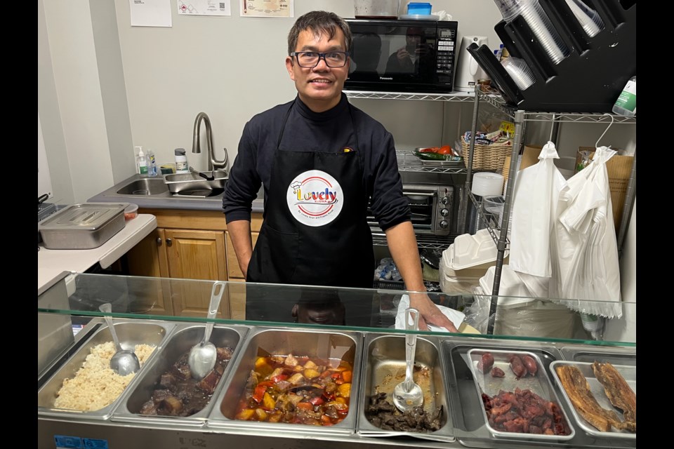 Luis Ereno stands behind the food he's serving up for lunch at Lovely Kusina within Lovely Asian and Filipino Goods.