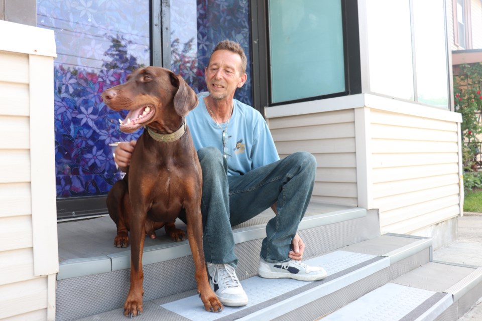 Lloyd Leroux and his dog Rosco sit on the same steps where he found a woman sleeping earlier this week before getting assaulted.