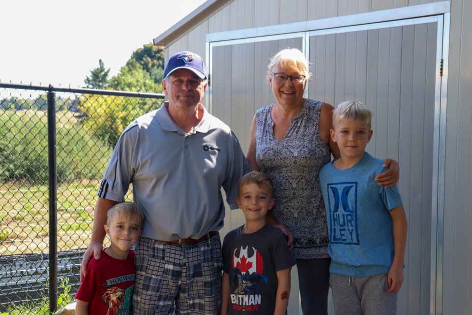 Dave and Cindy Clark stand with their grandchildren by the shed that could soon be expropriated by their neighbours.