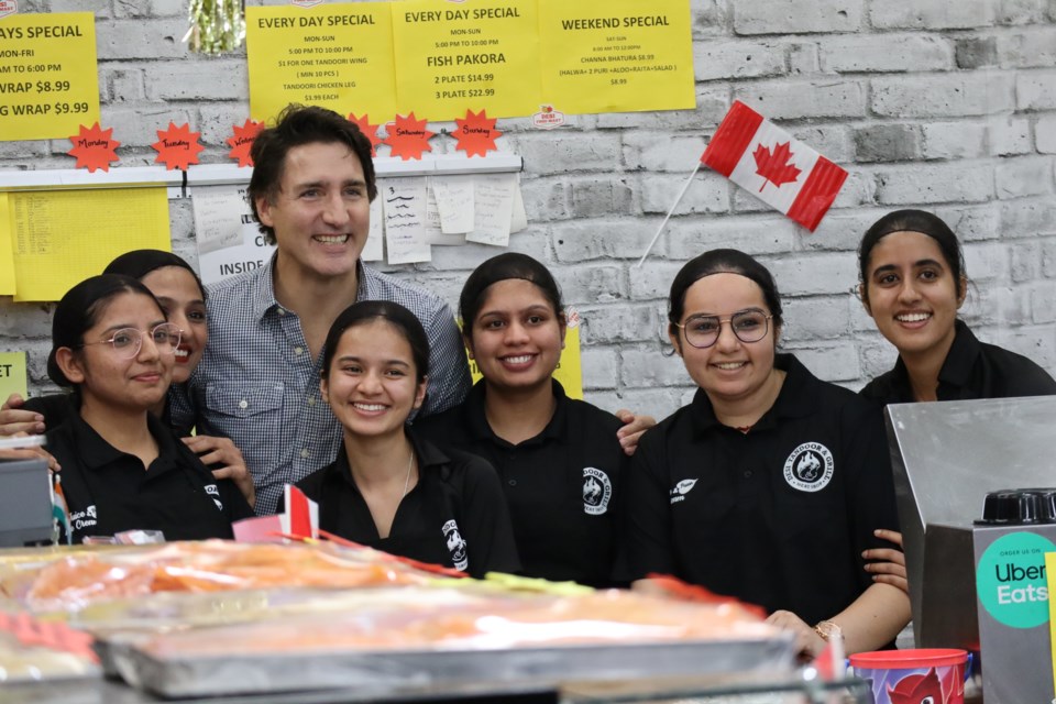 Prime Minister Justin Trudeau jumps behind the counter at Desi Food Market for a photo with staff.