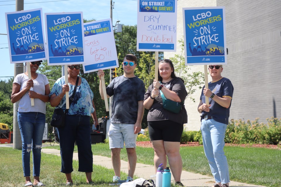 Workers at the Hespeler Road LCBO hold signs condemning premier Doug Ford 