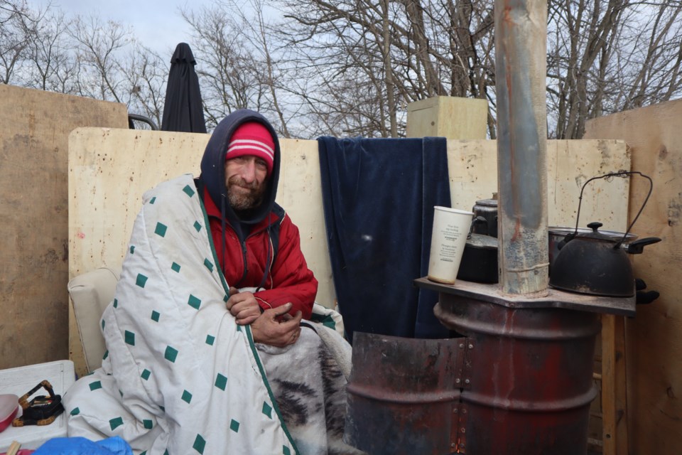 Russel Downie sits near his homemade heater after removing his belongings from the encampment Wednesday morning.