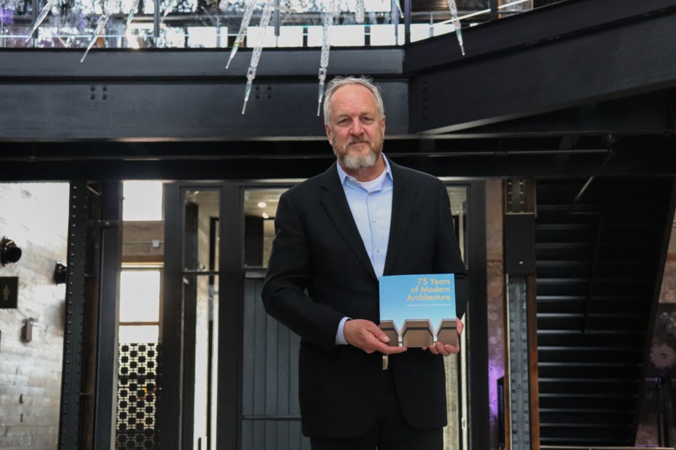 Patrick Simmons holds a new book celebrating the 75th anniversary of Martin Simmons Sweers inside Tapestry Hall.