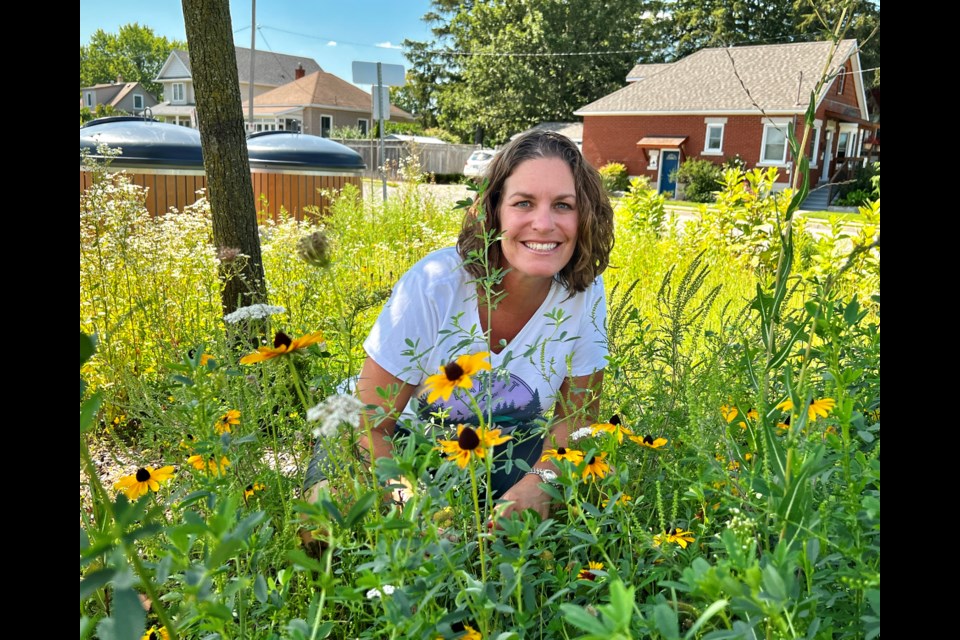 Grand View Public School principal Amanda Matessich peeks from behind some of the plants growing in the school’s new butterfly garden.