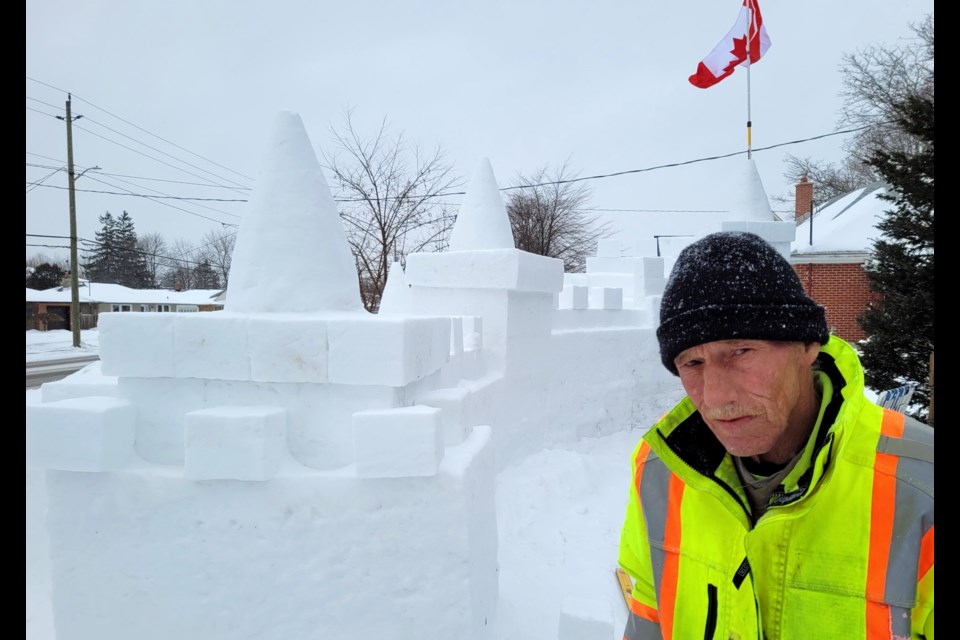 Cecil Devine stands beside the snow castle he built on the front lawn of his Concession Road home.