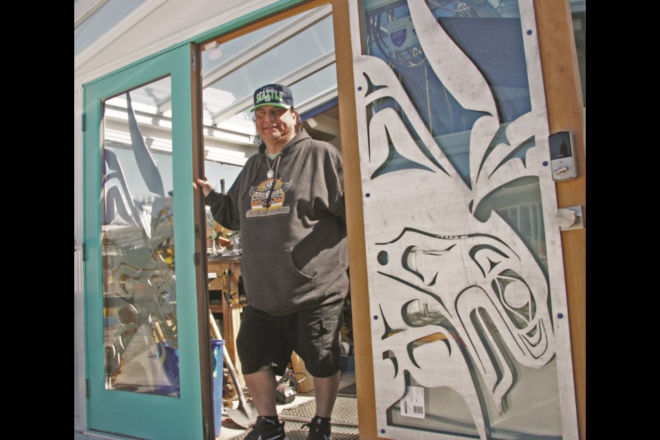 Derek Georgeson with the double doors entering his studio, which feature his metal blackfish design.  