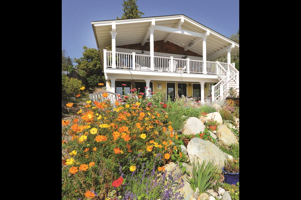 The view from the patio of this waterfront home looks out on a riot of flowering colours.