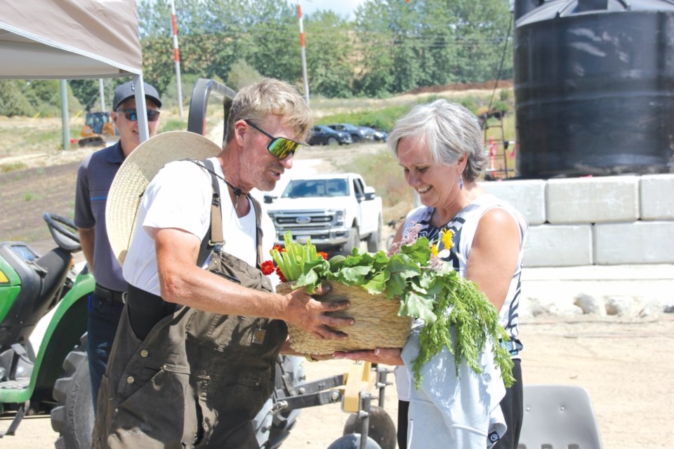 Kurtis Graham gifts a basket of the Salish Sea Regenerative Farm Society's first crop of produce to shishalh Nation lhe hiwus yalxwemult (Chief Lenora Joe). 