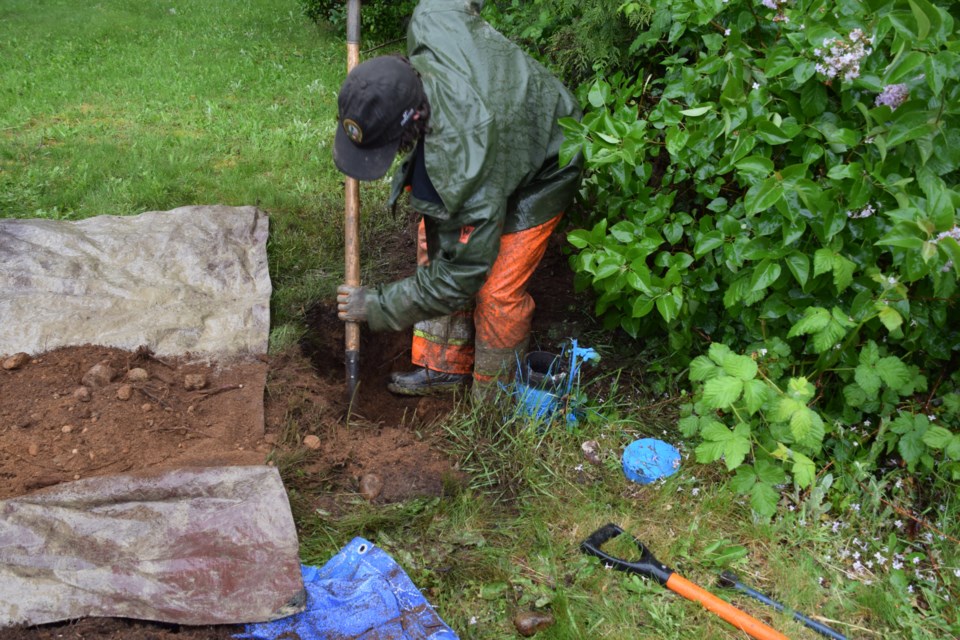 An employee of Neptune Technology hand digs the hole for a water meter installation on Sechelt's Wakefield Road.