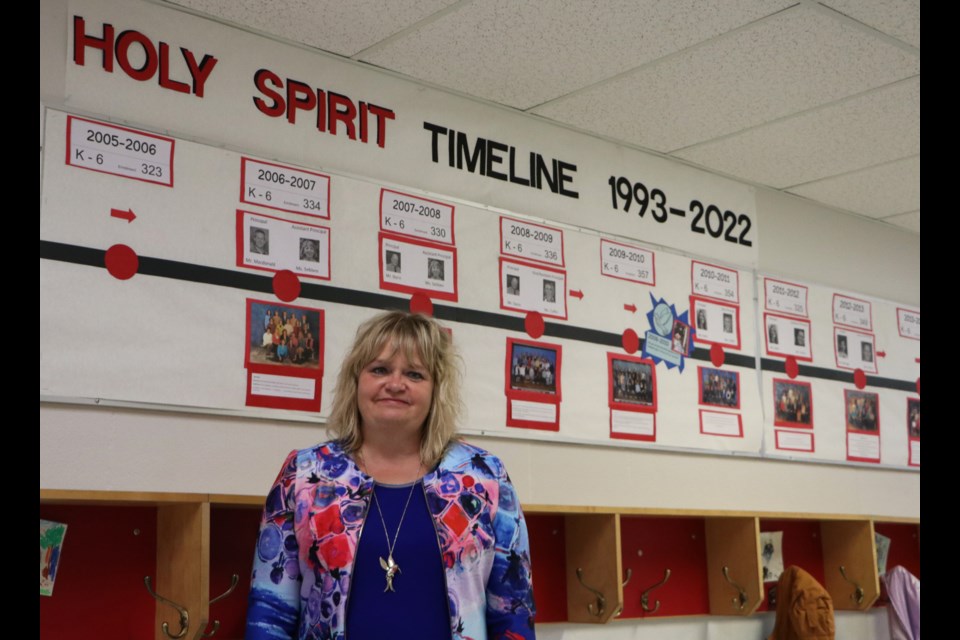 Principal Kim Welte stands in front of Holy Spirit School's timeline of events May 19. The display is set up for the school's farewell celebration next week as it prepares to move into the brand-new Fireside Catholic School in September 2022. (Jessica Lee/The Cochrane Eagle)