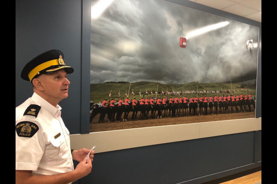 Insp. Dave Brunner in front of a picture of the 2019 RCMP Musical Ride performance in Cochrane. 