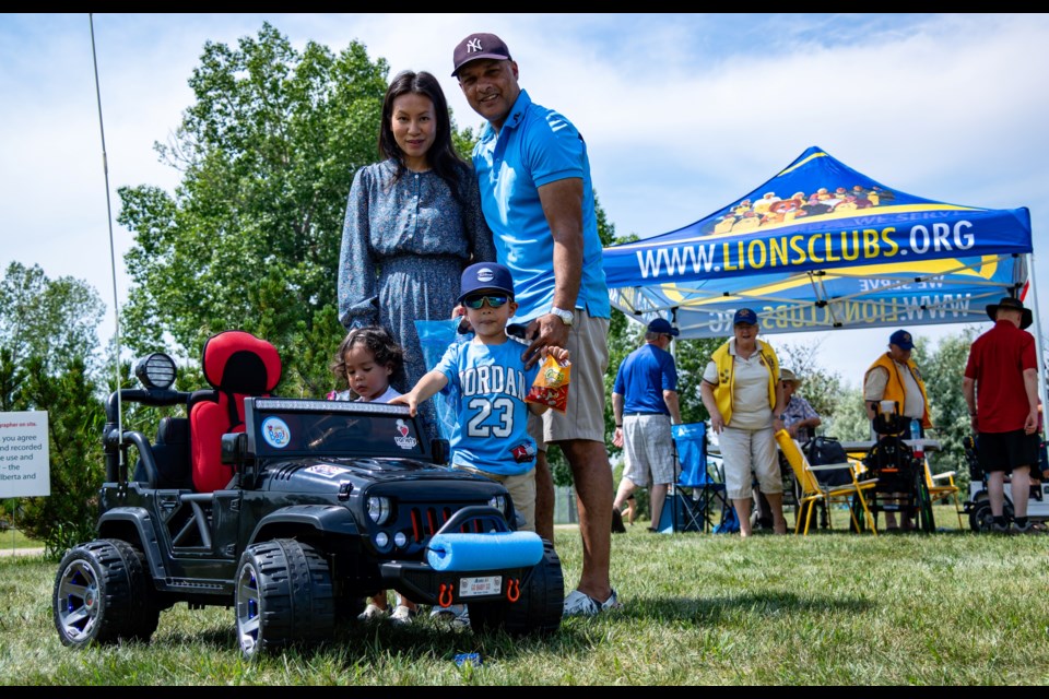 Julisa Khan, her husband Harris Khan, and their children, including Darrius and his brother Dariyaan, pose with Lions Club sponsor in the background during the event in South Glenmore Park, Calgary, Alberta, on Thursday, July 18, 2024. (Photo by Armaan Khanna/Cochrane Eagle)