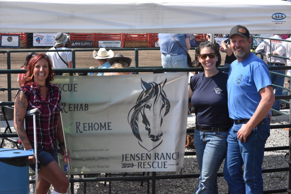 From left to right, Kendra Watt stands next to co-founders Kari Jensen and Cody Jensen, as they pose in front of their Jensen Ranch Rescue tent at the Calgary Police Rodeo