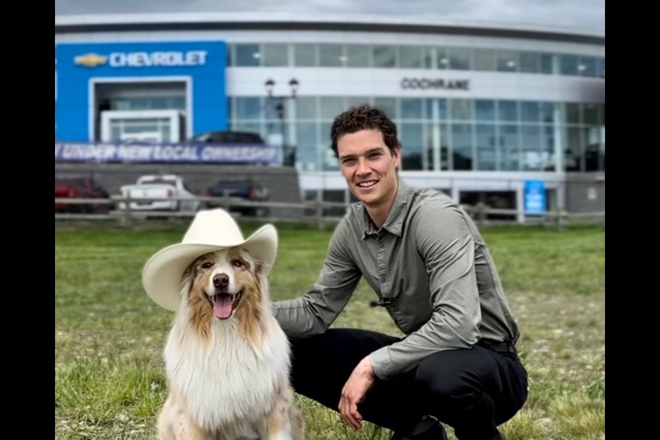 President of Cochrane GM and former NHL player Mason Raymond crouches with his dog outside of the dealership.