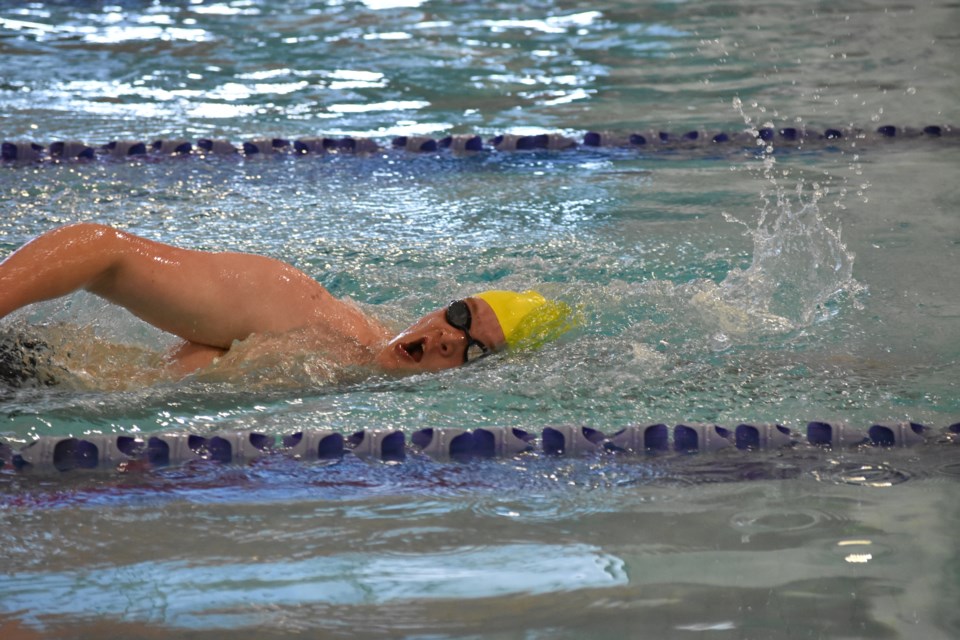 Boy in yellow cap swimming at the Cochrane Piranhas home meet 