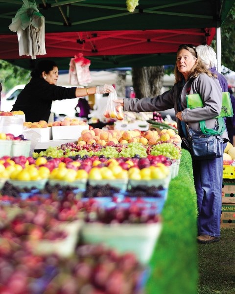 Dawne Clark, right, purchases fresh B.C. fruit at last year&#8217;s Cochrane Farmer&#8217;s Market.