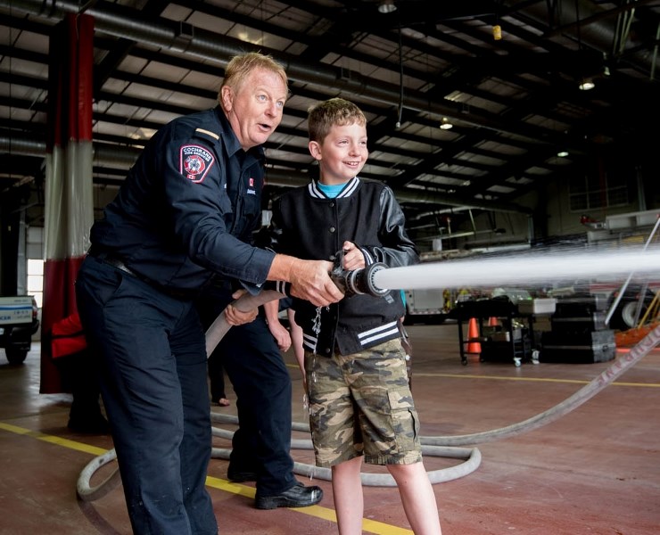 Cochrane Fire Services Lt. Jeff Avery teaches Kolton Stockwell, 9, how to handle a fire hose during the Doors Open event in Cochrane on Saturday, June 10, 2017.