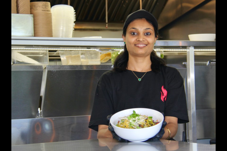 Collingwood Noodlebox staff Dinal Patel is seen with a bowl of Thai style chow mein with chicken.