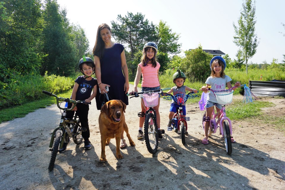 From left to right, Nash, 6, Christal Blanchard with her dog Maverick, Arya, 8, Cruz, 3 and Talia, 6, ride along the Hamilton Drain Trail where it meets the Train Trail on Aug. 10, 2023.