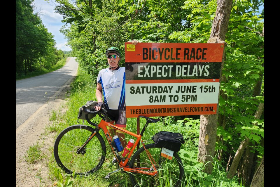 Local resident Bill Abbotts with a sign advising motorists of the upcoming gravel bike race in The Blue Mountains.