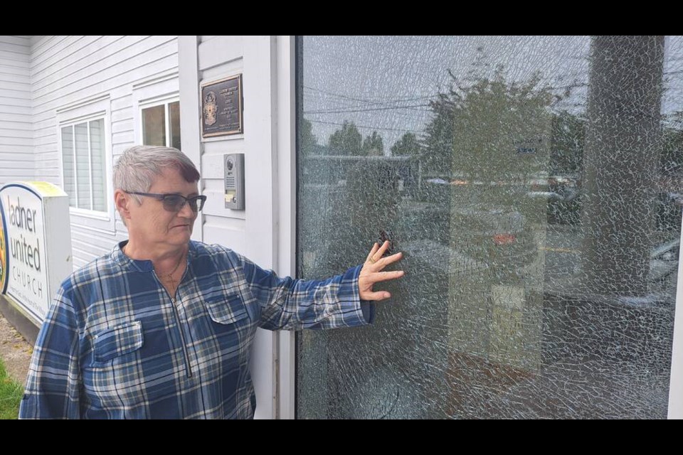 Ladner United Church minister Nancy Painter points to the shattered window vandalised early Monday morning. Phil Melnychuk Photo